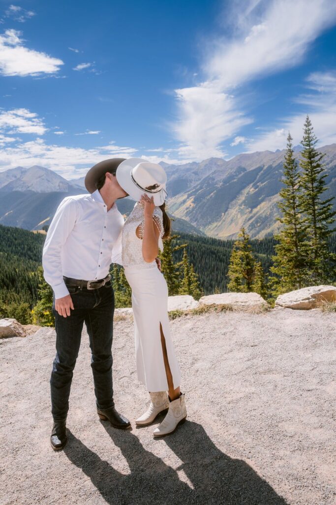 portrait by laura stone photo of bride and groom kissing on a mountain top at their wedding venue in aspen colorado