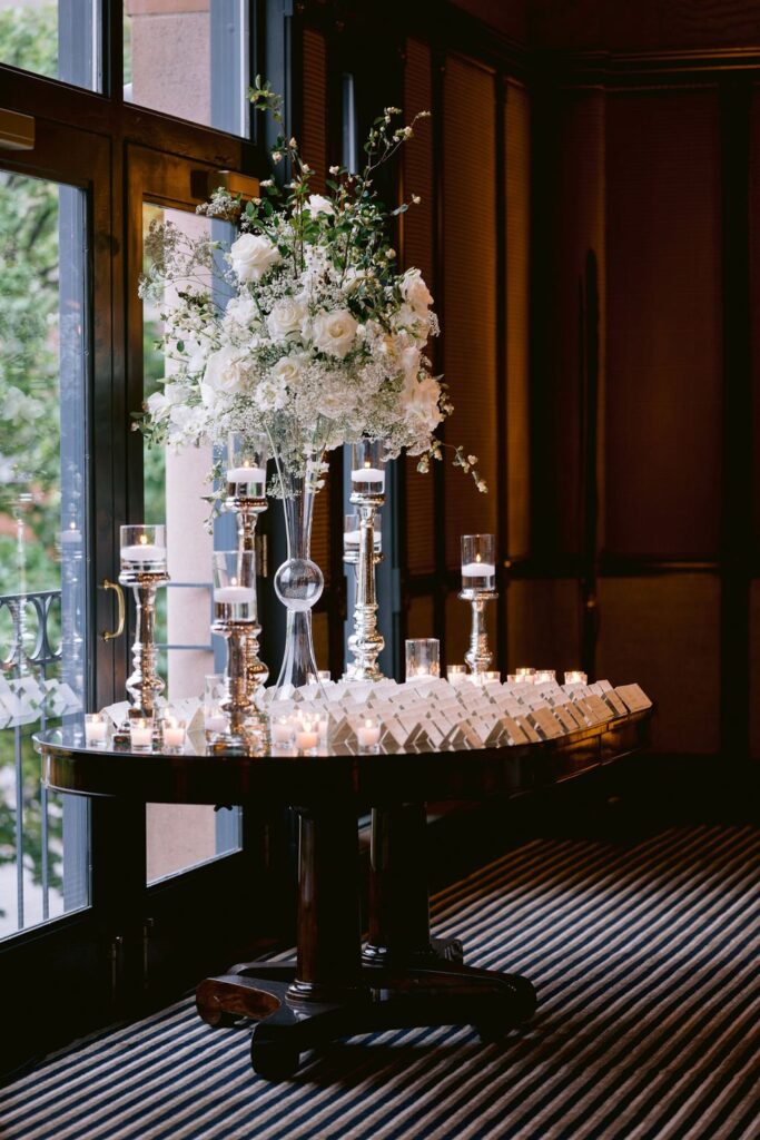 table with large white flower bouquet and wedding placecards setup in hotel jerome aspen