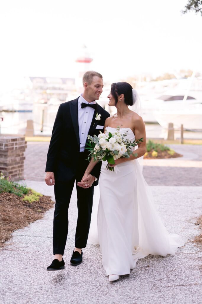 bride and groom lovingly smiling at each other while walking to their sea pines resort wedding reception venue