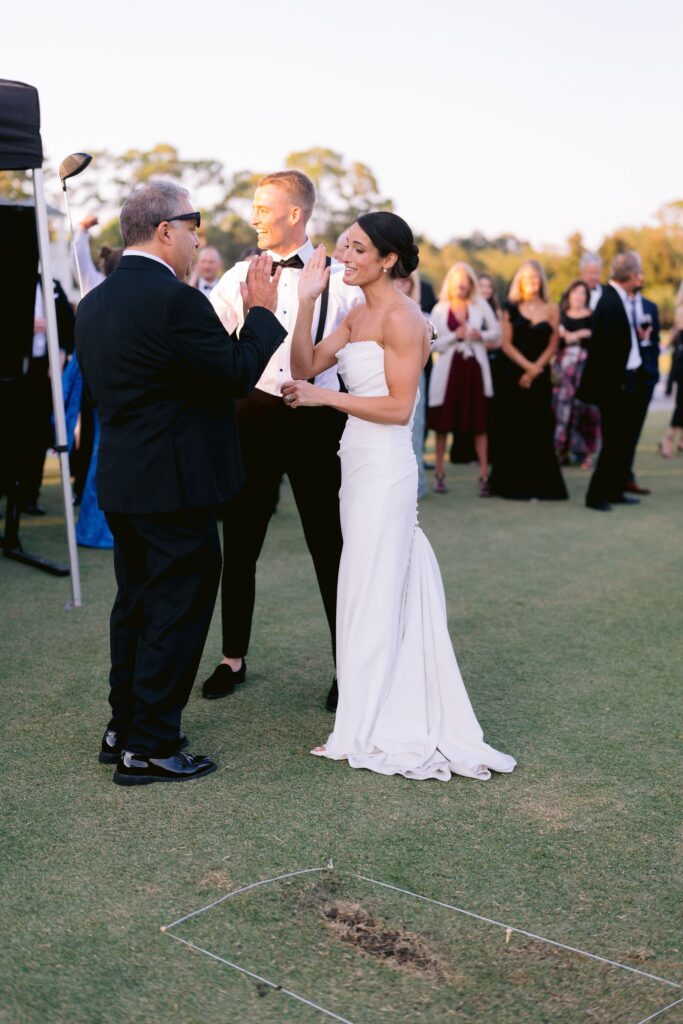 bride high-fiving her wedding guest on the golf course at sea pines resort