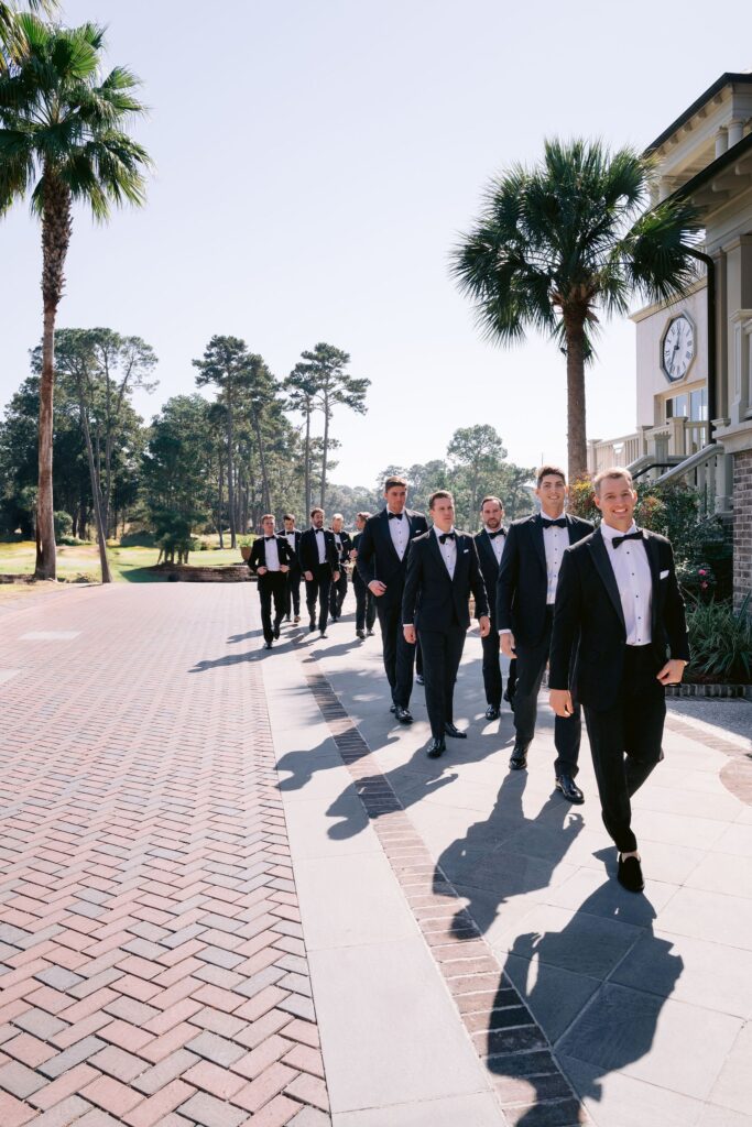 photograph by laura stone photo of groom and his party walking down a brick path during his sea pines wedding