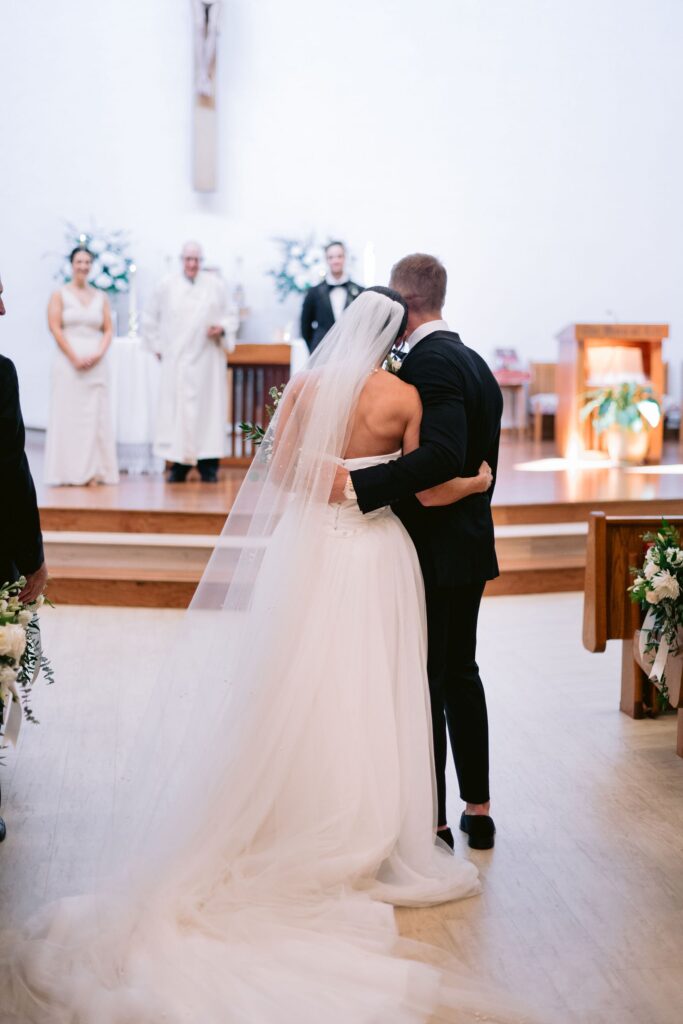 bride and groom embracing each other in St. Francis by the Sea Catholic Church at their sea pines wedding