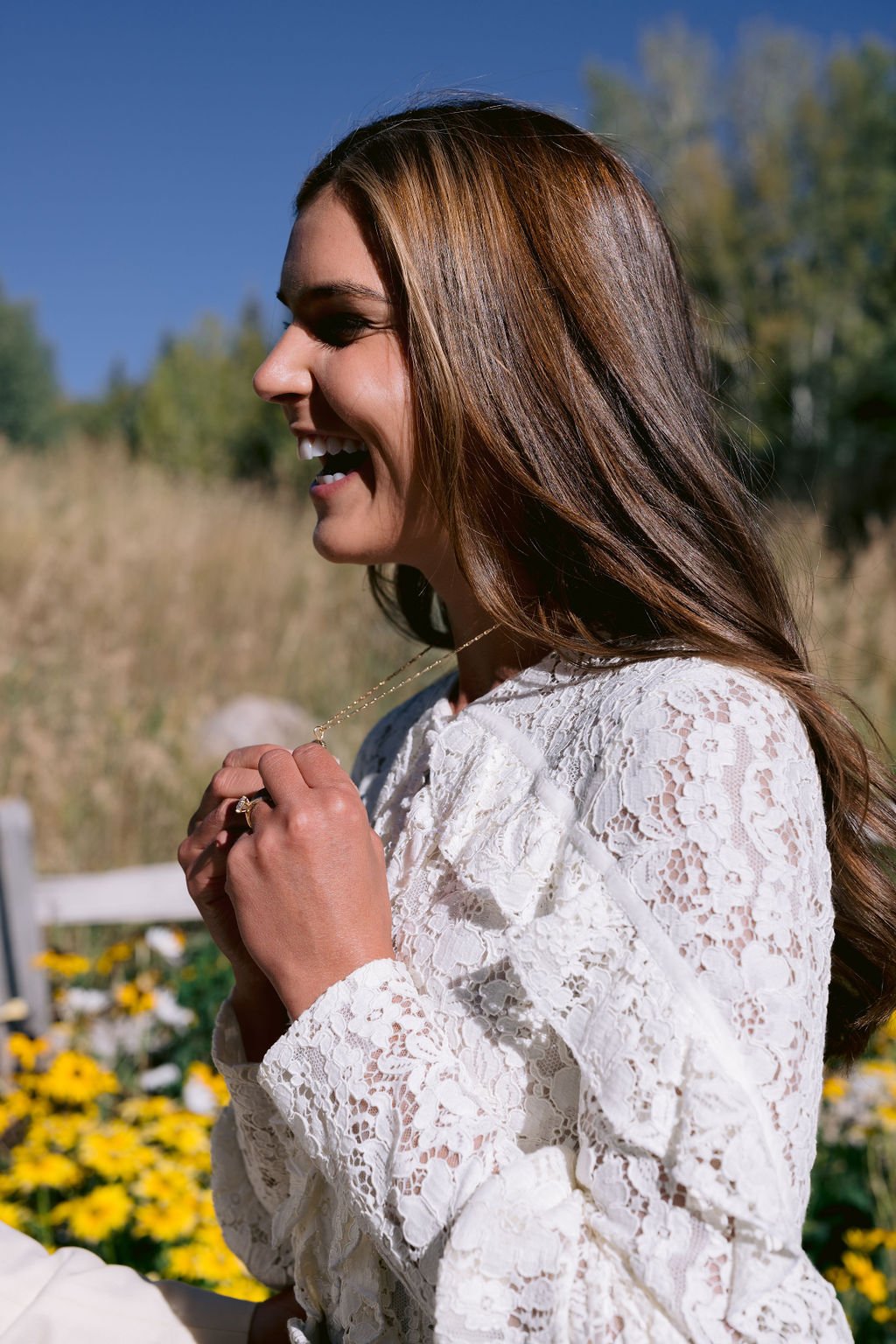 bride smiling while holding her necklace during her aspen meadows resort wedding portrait session