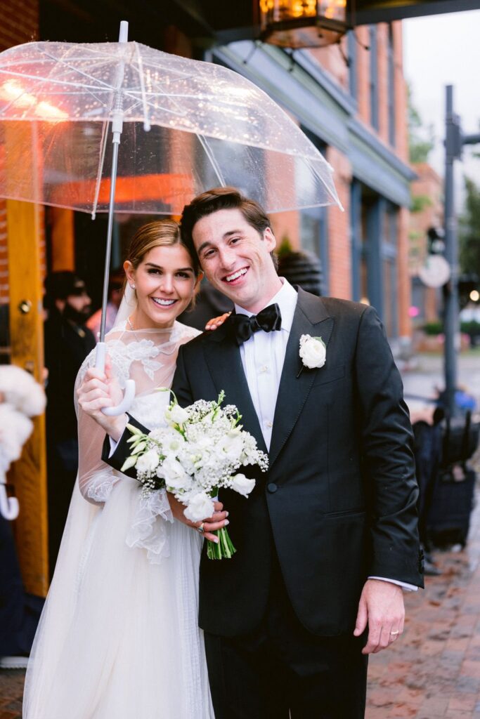 bride and groom smiling for a photo in front of hotel jerome aspen during their wedding