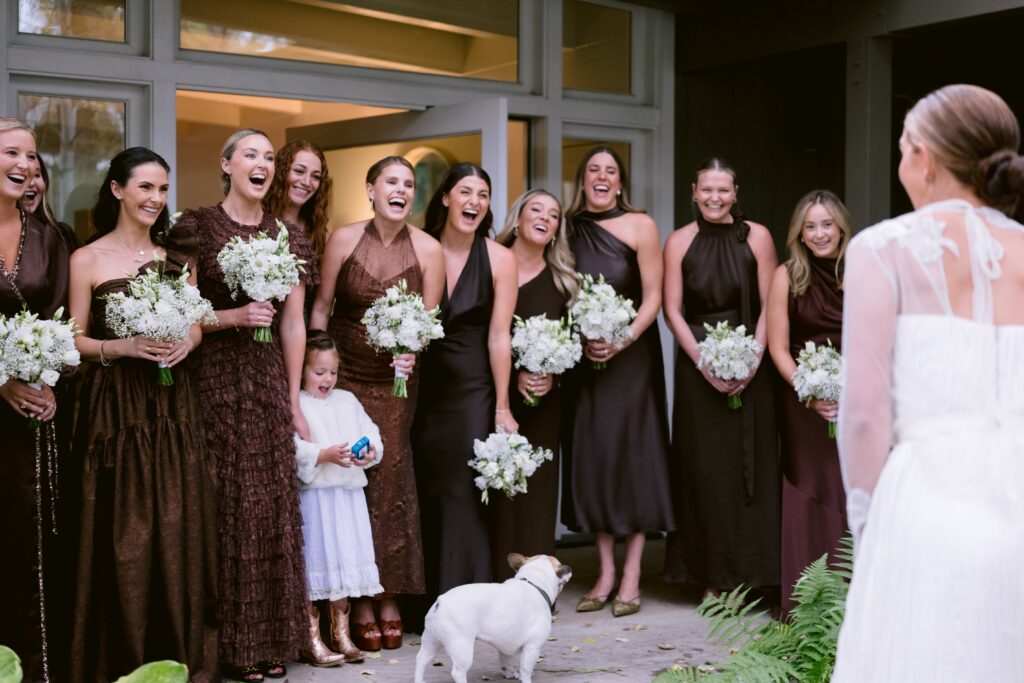 bridesmaids in brown dresses laughing during a first look with the bride at a luxury aspen wedding