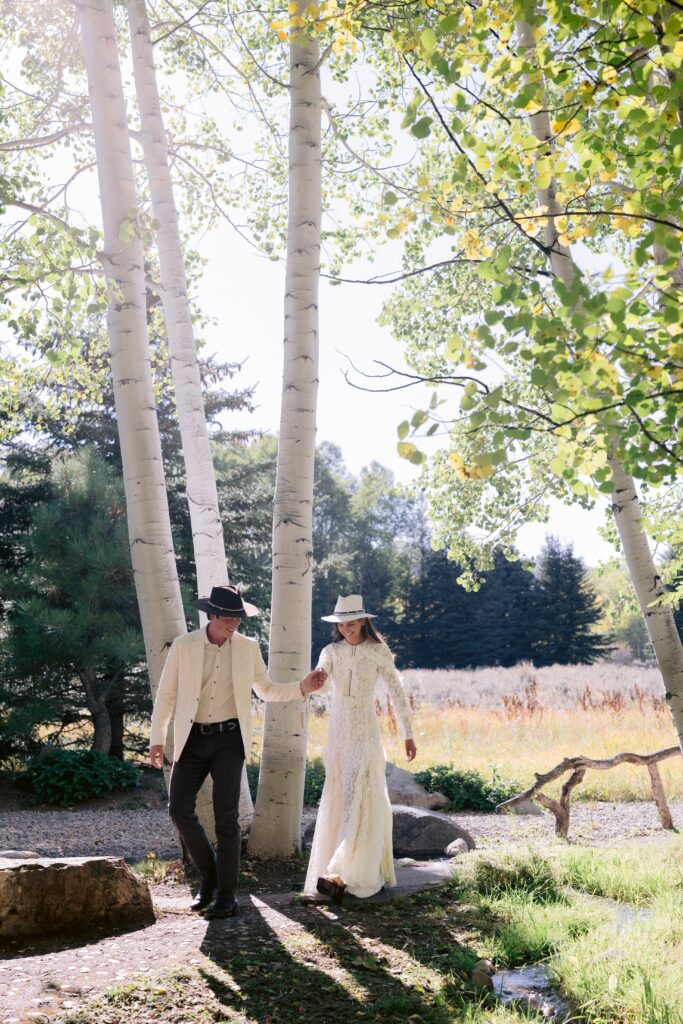 couple walking through a grove of aspen trees at their aspen wedding, surrounded by natural beauty and absolute privacy