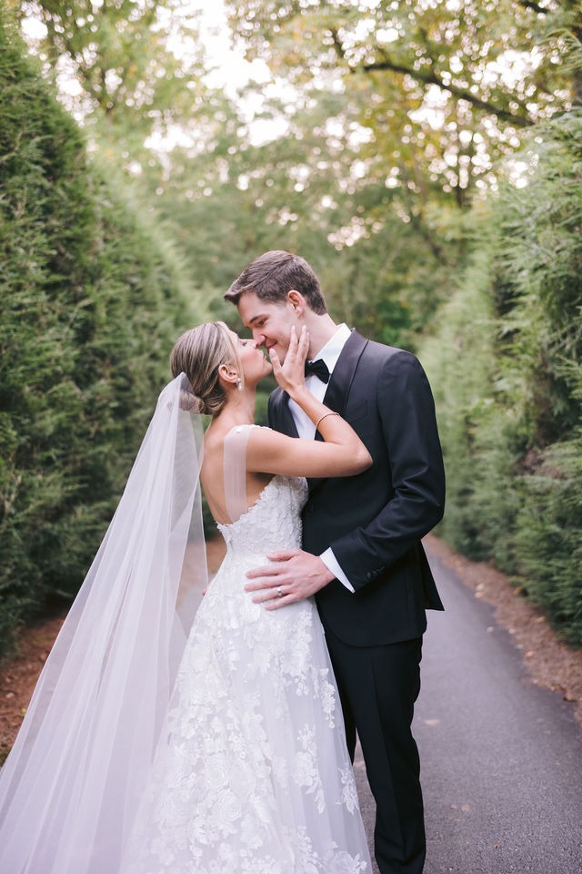 bride and groom sharing a kiss during their portrait session on the paved pathway surrounded by greenery at old edwards inn half-mile farm