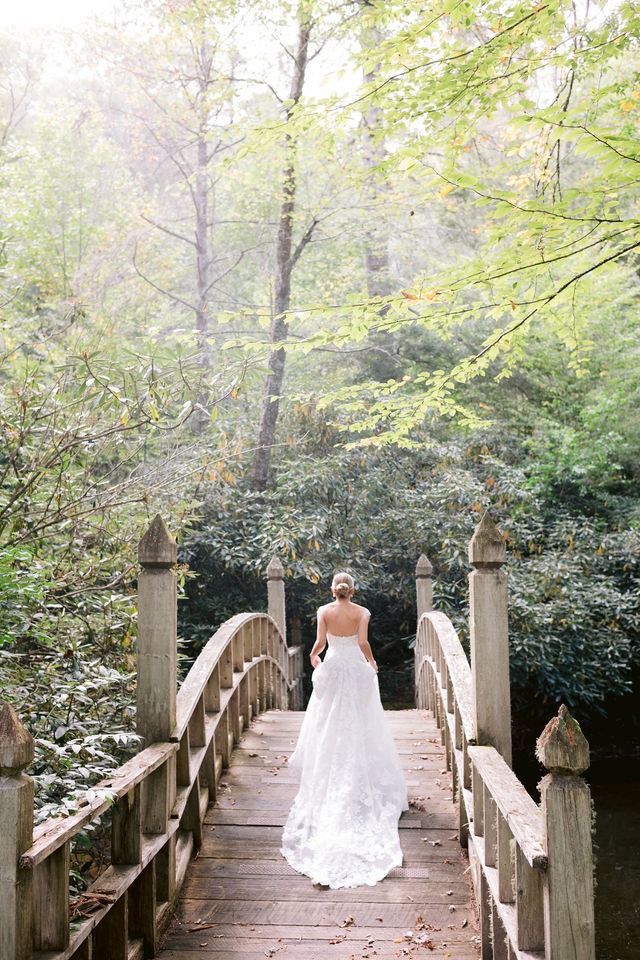 portrait of a bride crossing a wooden bridge at old edwards inn half-mile farm