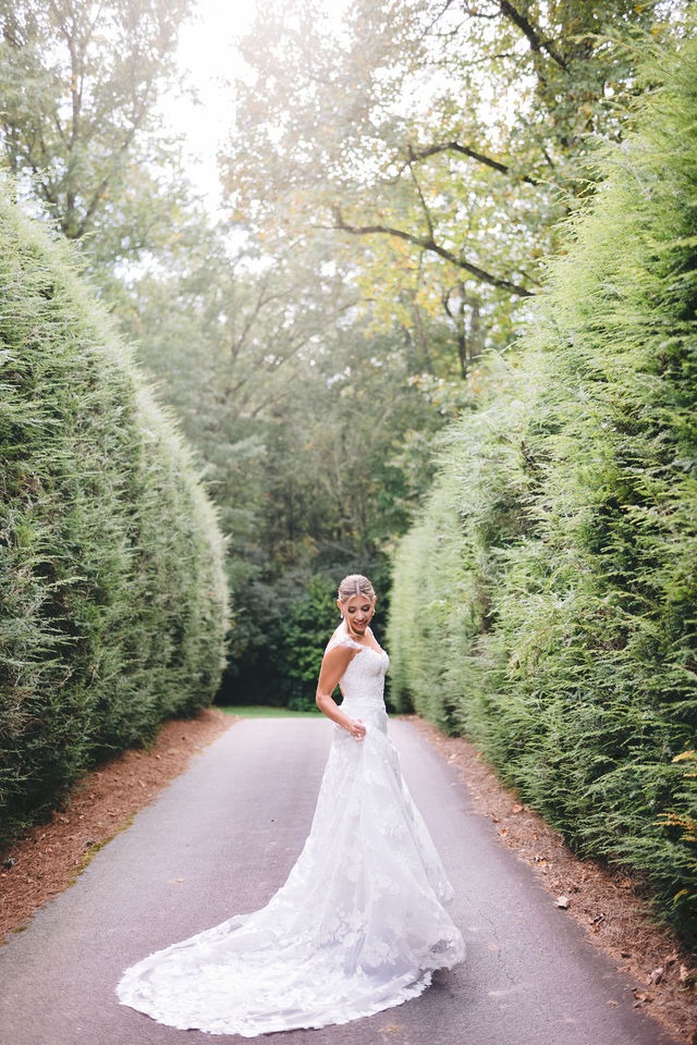 portrait of a bride twirling in her wedding dress during on a pathway surrounded by greenery during her half-mile farm wedding