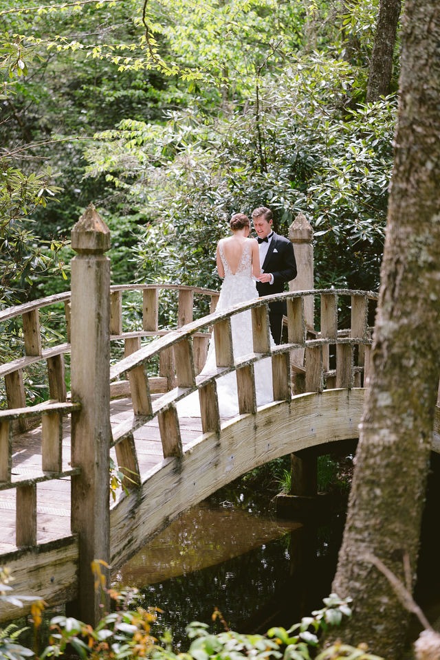 bride and groom sharing private vows on a wooden bridge during their first look at their highlands nc wedding venue