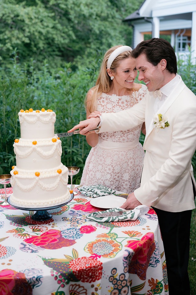 portrait of a bride and groom smiling while cutting their wedding cake during their wedding at half mile farm old edwards inn