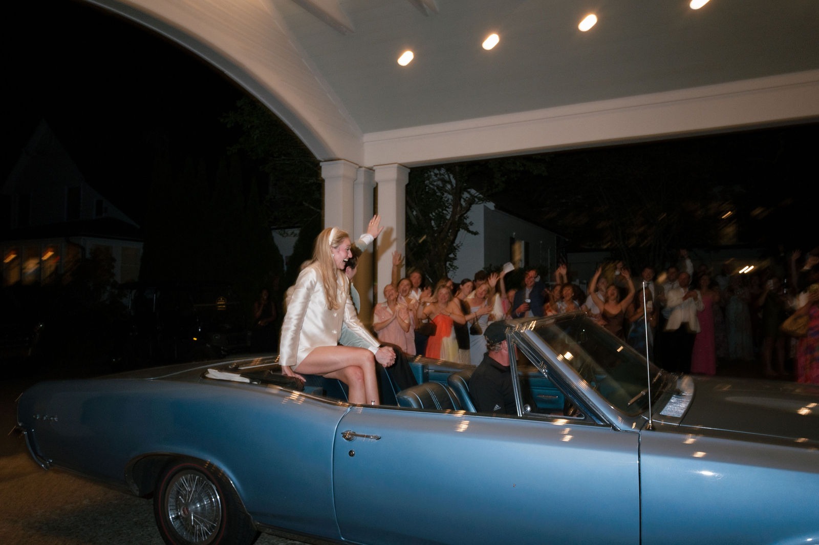 bride and groom sitting on a blue car ready to drive away from their old edwards half mile farm wedding reception
