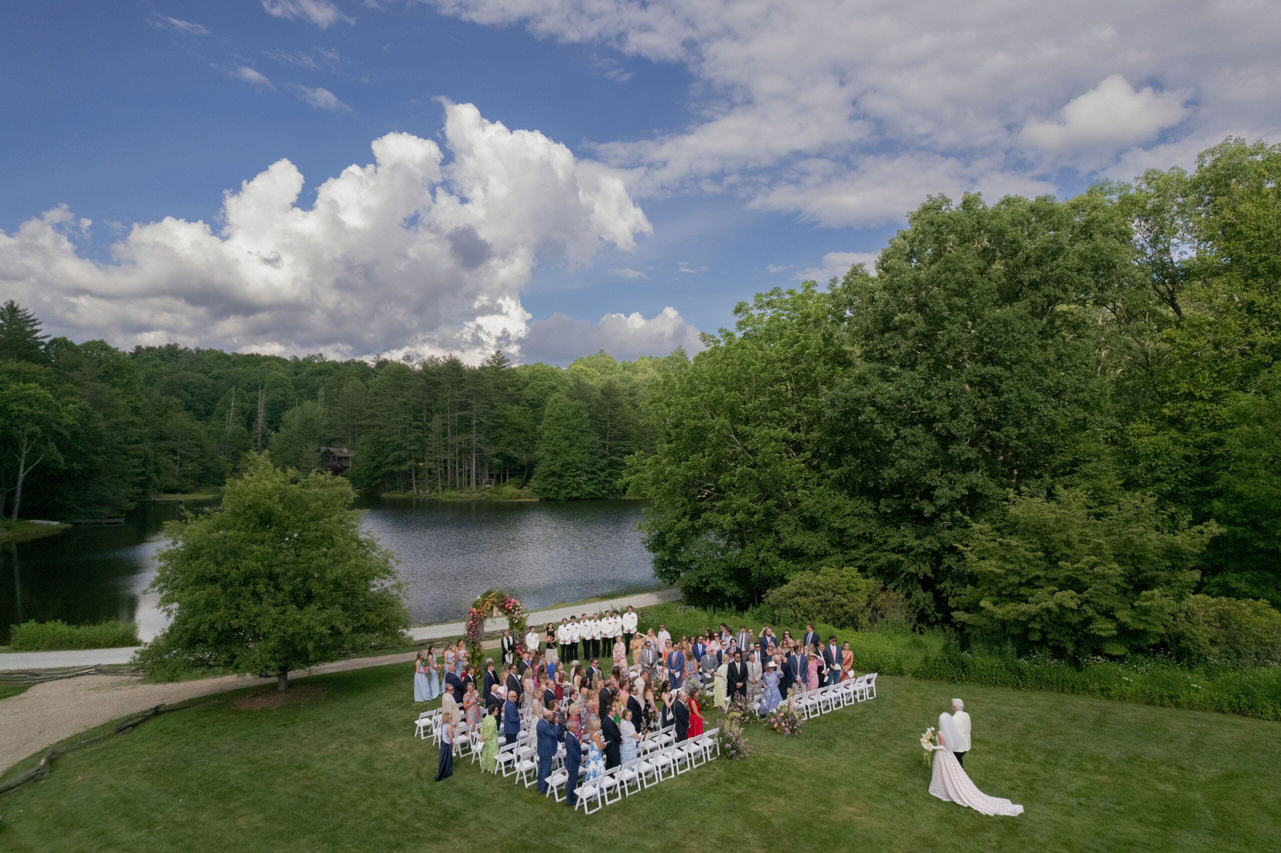 guest gathered on the lawn by the lake at old edwards half mile farm for a wedding ceremony