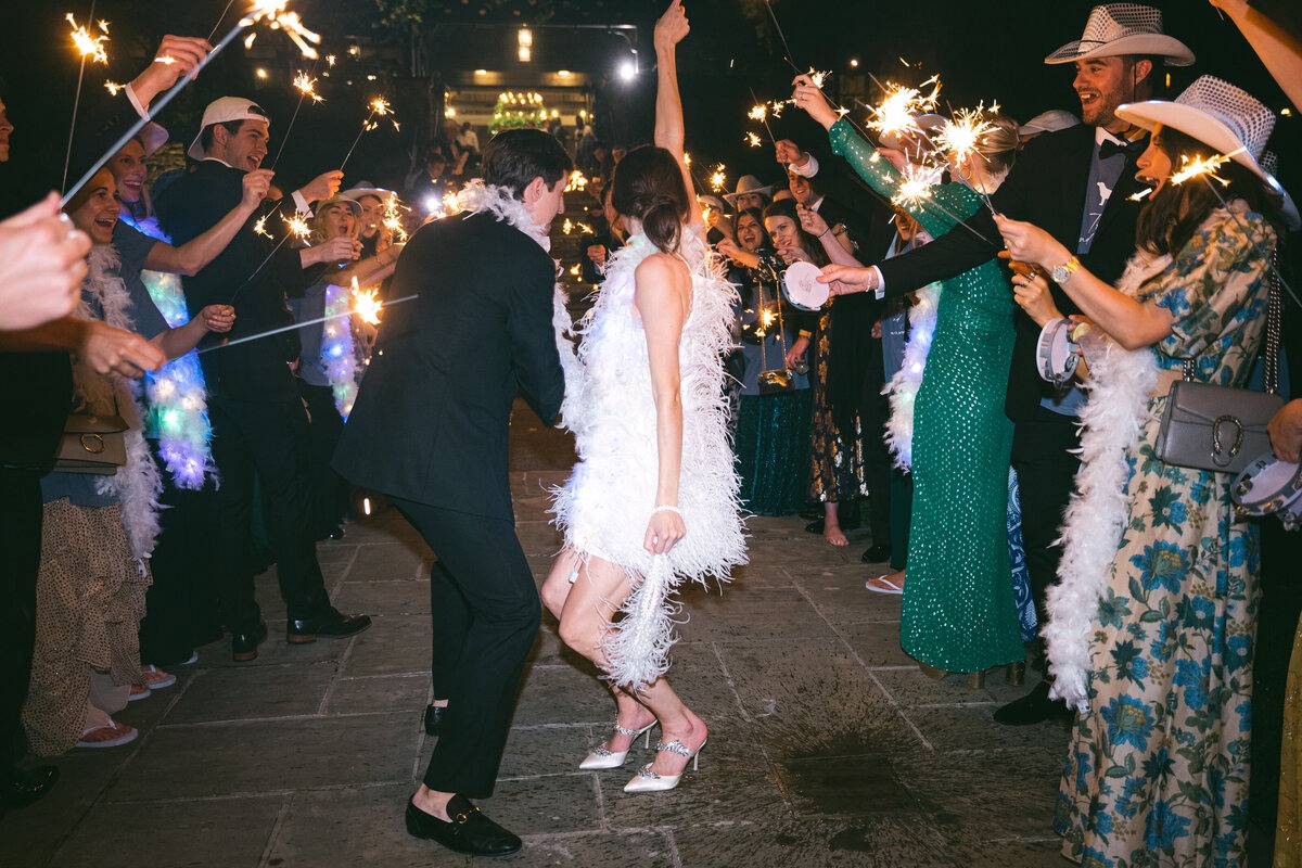Bride and groom dancing through a sparkler exit surrounded by their wedding guests.